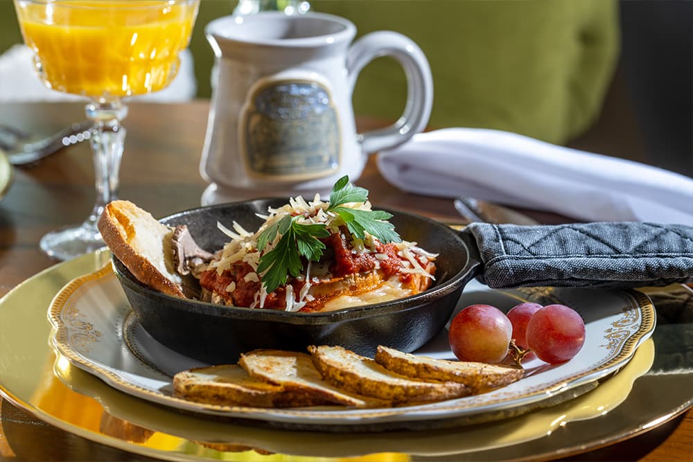 A mouthwatering breakfast skillet with melted cheese, served with fresh fruit and a beverage