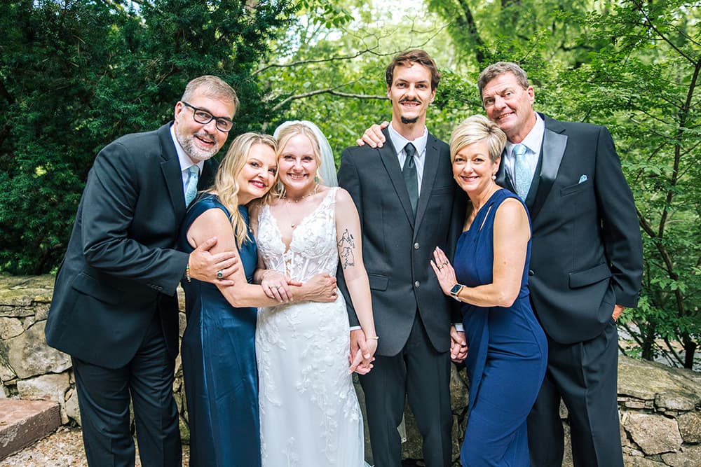 Happy married couple with family members hugging each other.