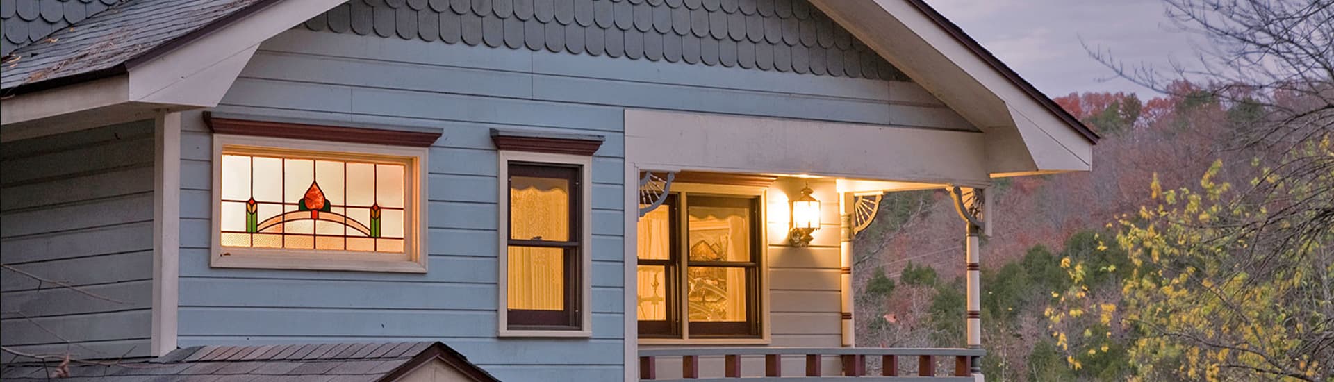 Charming bed and breakfast with a blue facade, a stained glass window, and a porch with a railing.