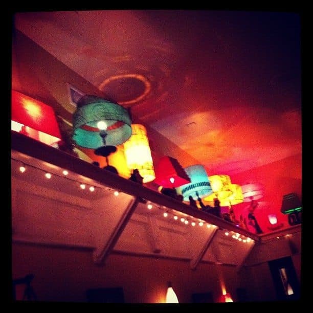 Colorful lamps line the wall beneath a vividly painted ceiling. Colorful lamps line the wall beneath a vividly painted ceiling.