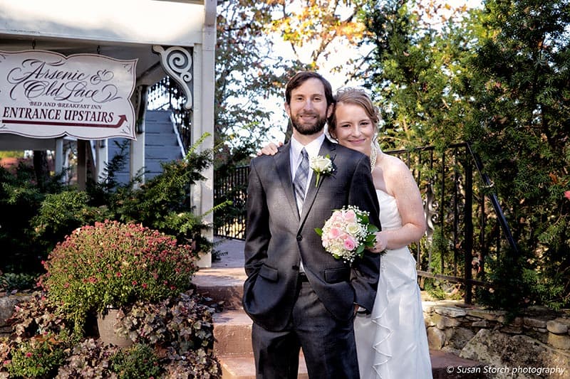 A happy couple poses together outside a venue, with the bride holding a bouquet and the restaurant sign visible in the background.