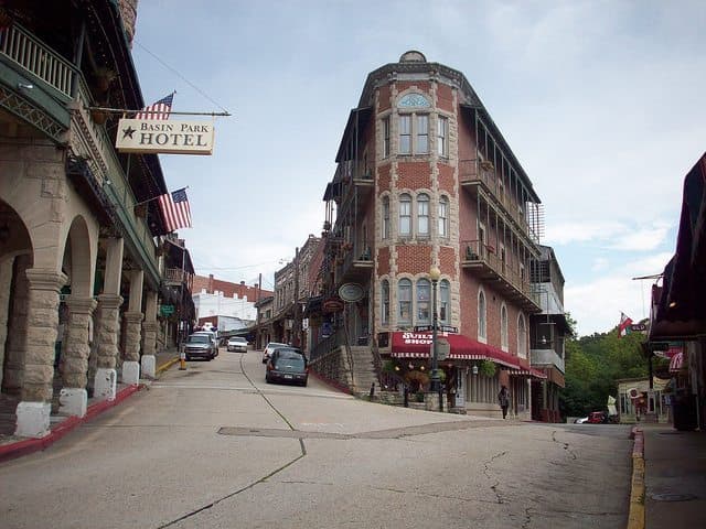 A steep street lined with historic buildings and the Basin Park Hotel in an old town setting.