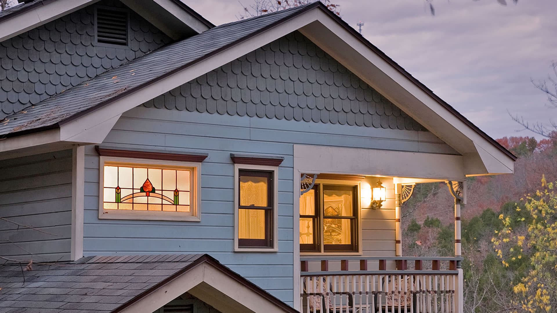 The bed and breakfast has a gently sloping roof, a hallmark of Craftsman homes.  Backlight with interior lighting at dusk.
