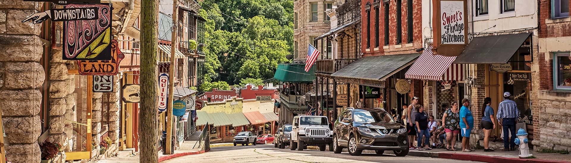 A bustling street in downtown Eureka Springs, Arkansas, with historic buildings, shops, and pedestrians.