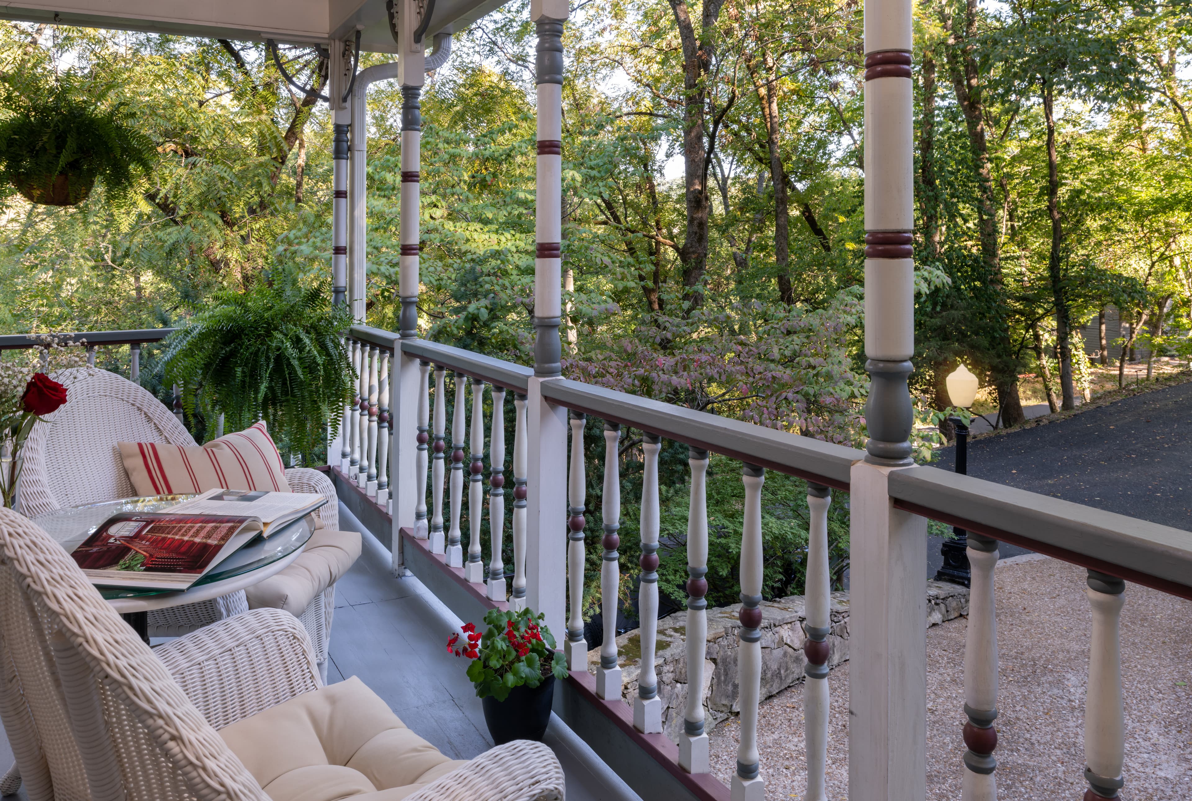 A cozy porch with wicker furniture overlooks a lush green landscape.