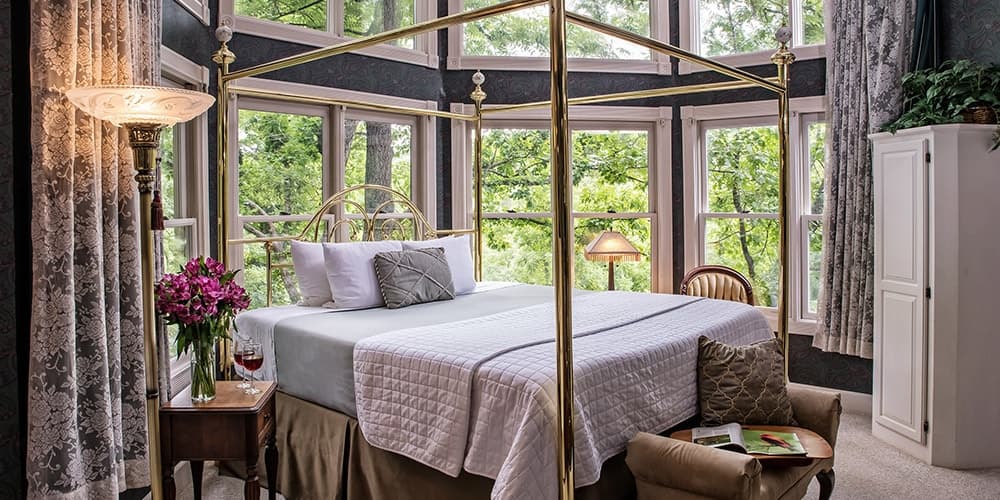 A cozy bedroom with a four-poster bed, large windows, and elegant decor.