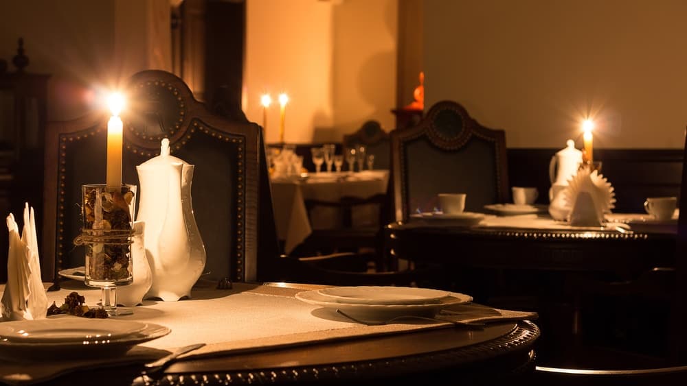 A dimly lit, elegant restaurant setting with candlelight illuminating the tables and chairs.