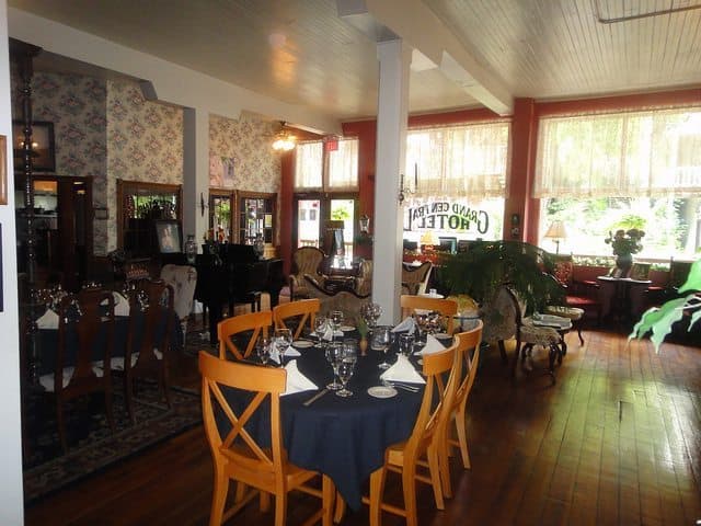 A cozy dining area in an elegant restaurant with wooden tables, decorative glassware, and floral wallpaper. A cozy dining area in an elegant restaurant with wooden tables, decorative glassware, and floral wallpaper.