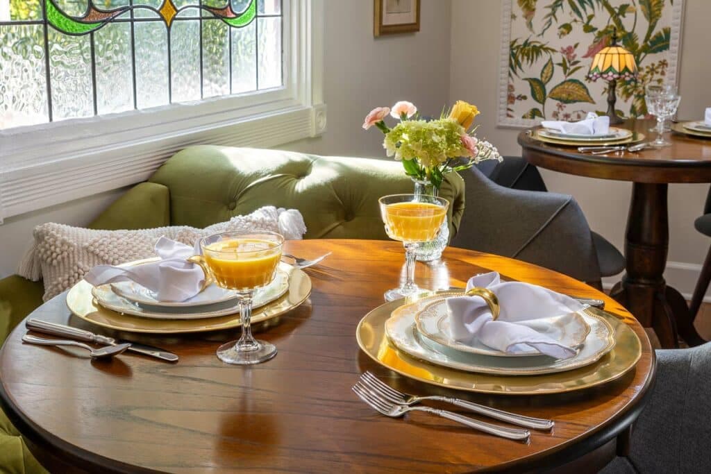 A cozy dining table set with two place settings, including plates, silverware, napkins, and glasses of juice.