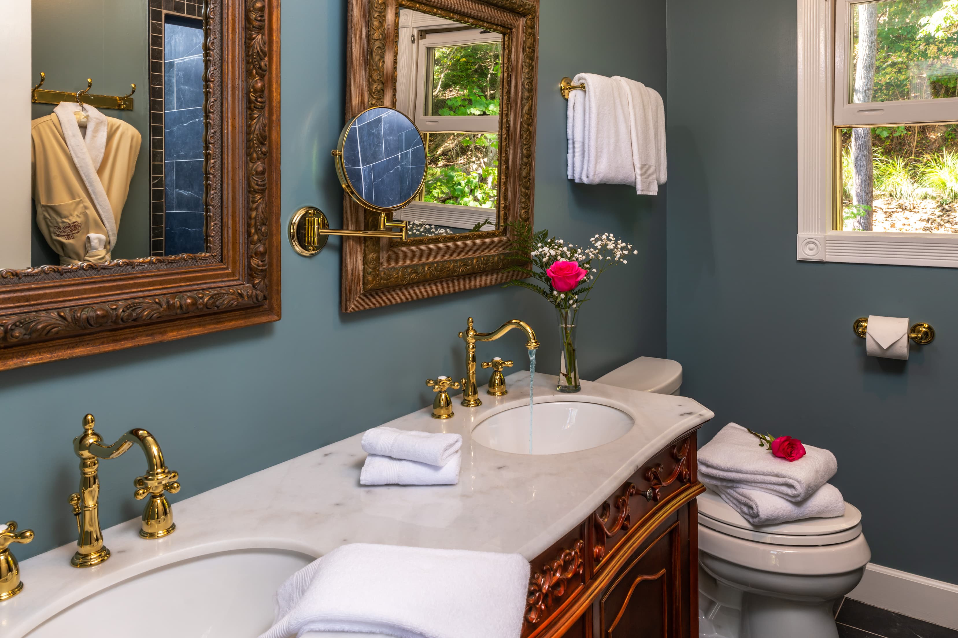 Elegant bathroom featuring dual sinks, ornate mirrors, and decorative towels.