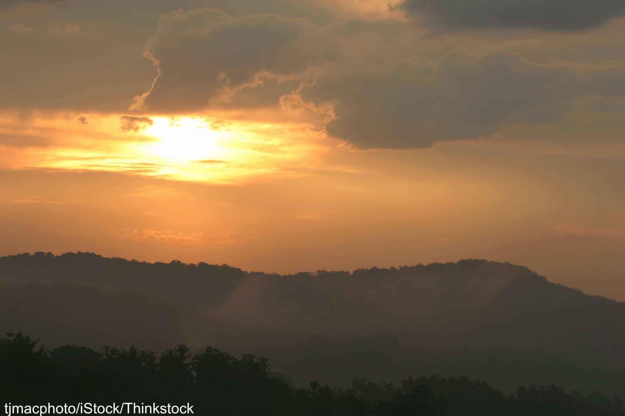 Sunset over rolling hills with dramatic cloud formations.