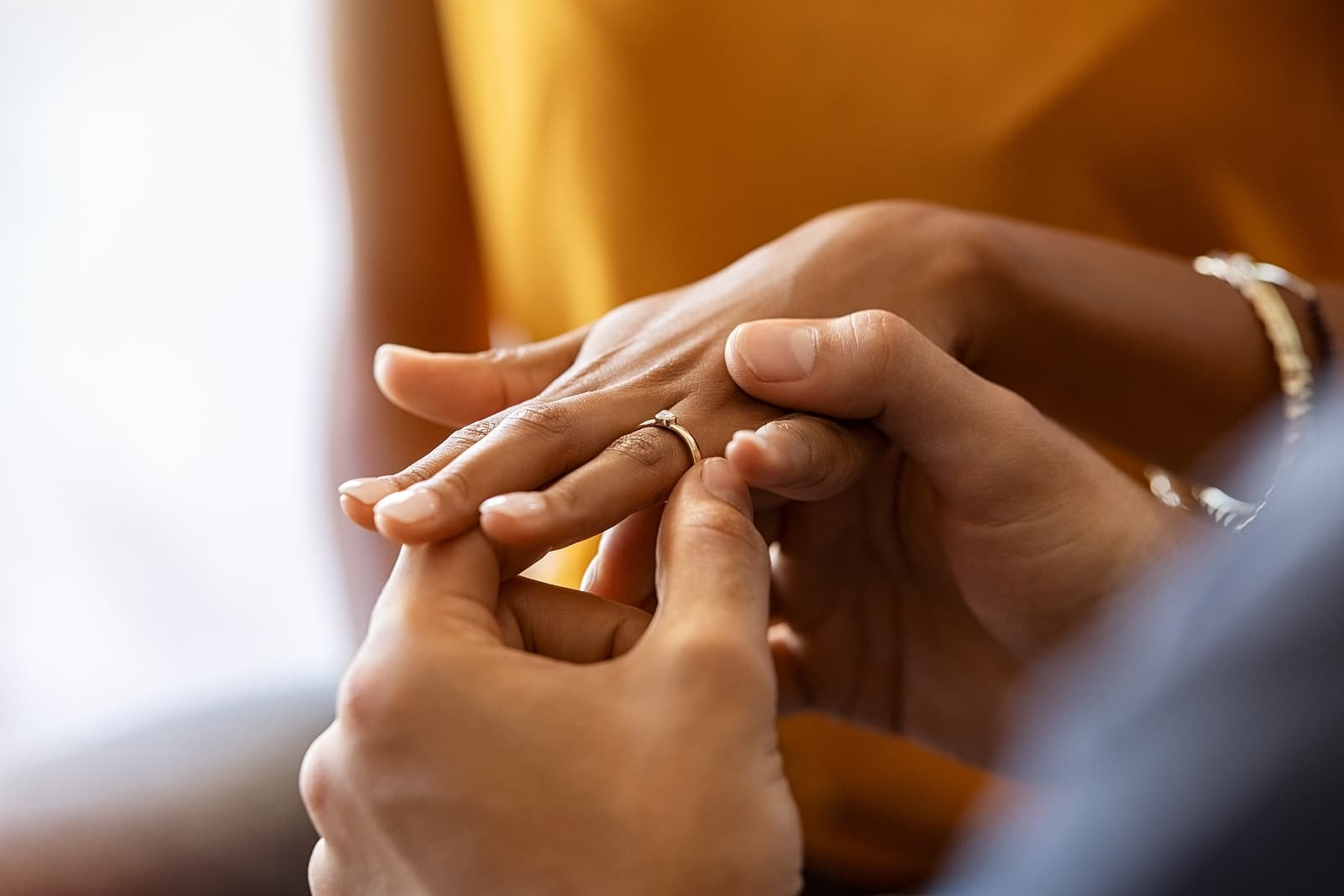 A person puts a ring on another person's finger in a tender moment.