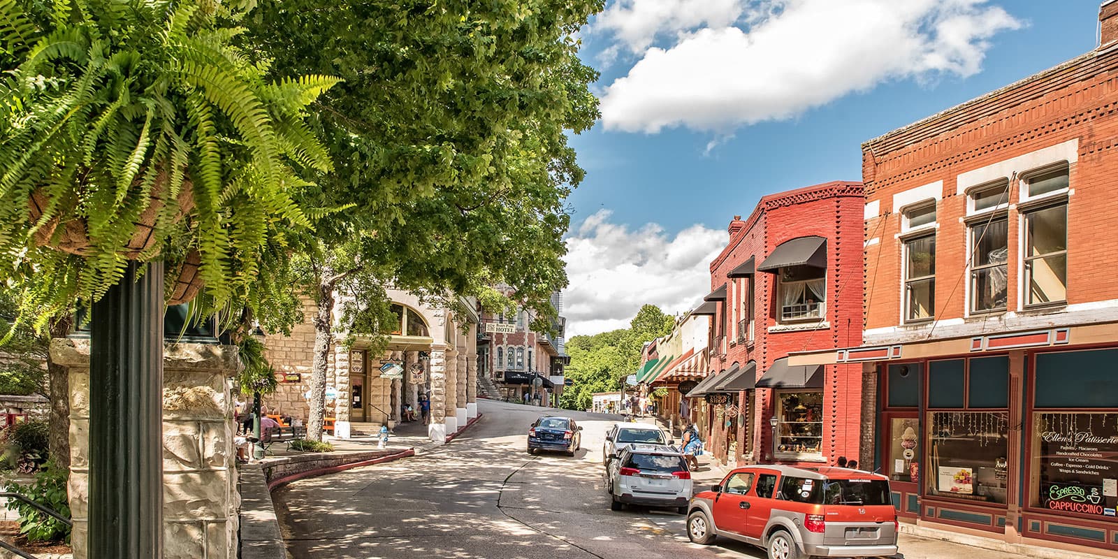 A picturesque street with shops and trees under a blue sky.