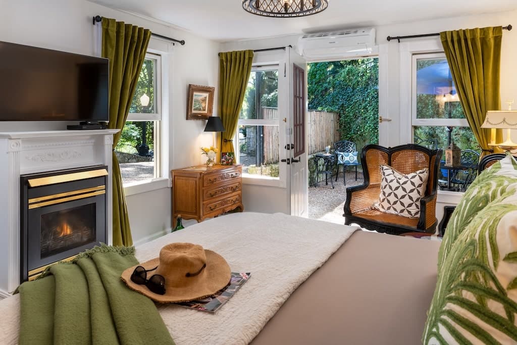 Cozy bedroom featuring a fireplace, a view of a garden, and stylish furnishings.