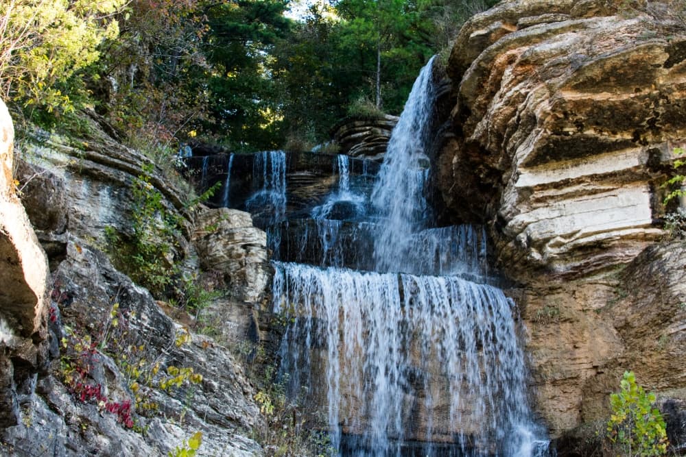 A cascading waterfall flowing over rocky cliffs surrounded by lush greenery. A cascading waterfall flowing over rocky cliffs surrounded by lush greenery.