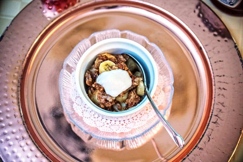 A bowl of oatmeal topped with banana slices and yogurt.