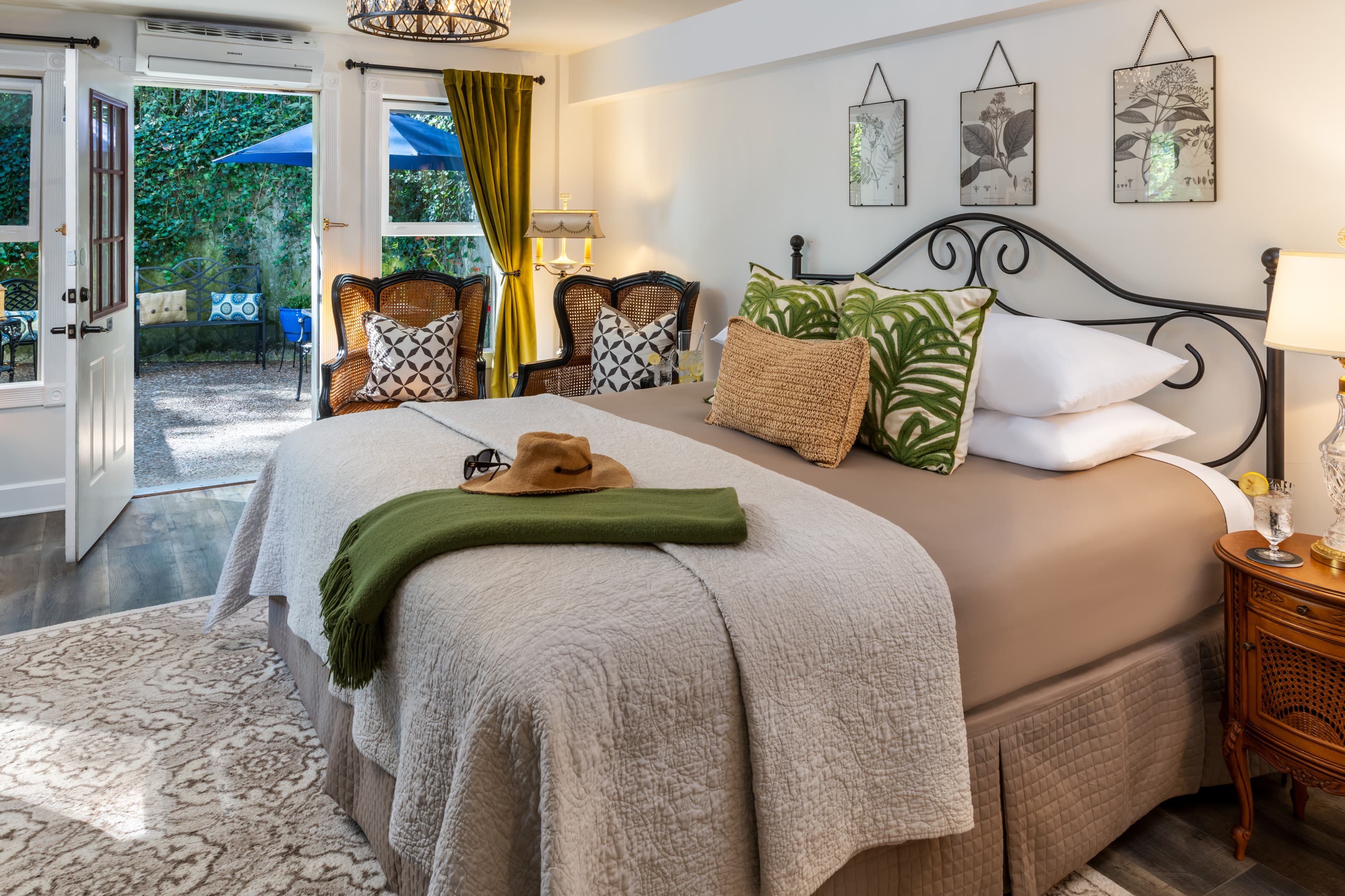 Cozy bedroom featuring a large bed, decorative pillows, and a view of a patio with outdoor seating.