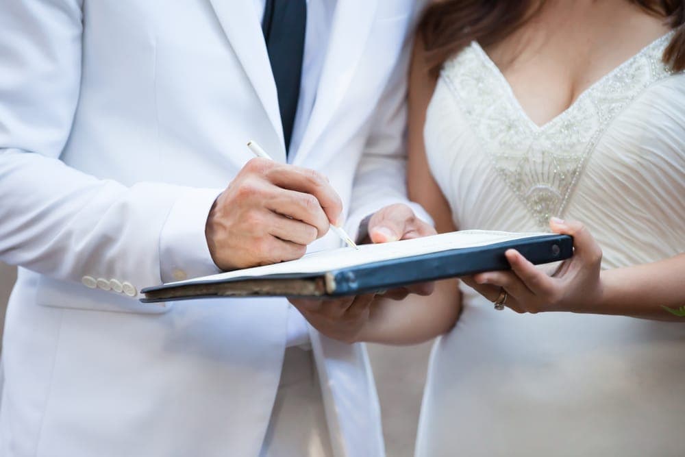 A couple signs a document together during their wedding ceremony. A couple signs a document together during their wedding ceremony.