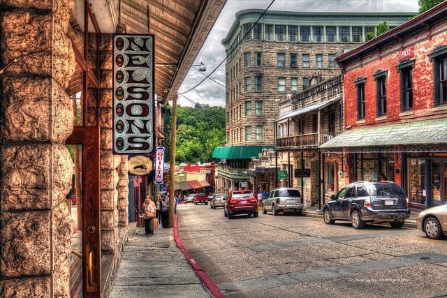Historic street scene featuring Nelson's sign, bustling shops, and parked cars.