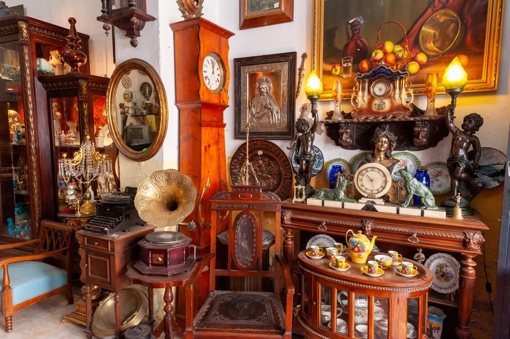 A cluttered antique shop filled with various vintage items, including clocks, mirrors, and a gramophone. A cluttered antique shop filled with various vintage items, including clocks, mirrors, and a gramophone.