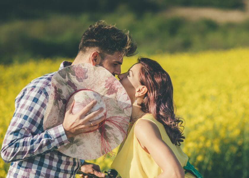 A couple shares a kiss in a field of yellow flowers. A couple shares a kiss in a field of yellow flowers.