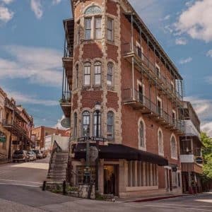 Historic brick building on a sloped street under a blue sky.