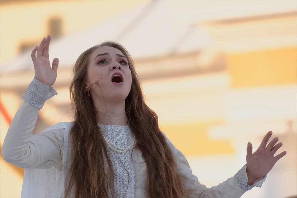 Opera singer belting music with yellow background.