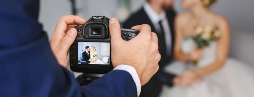 A photographer captures a couple in formal attire on a camera screen.