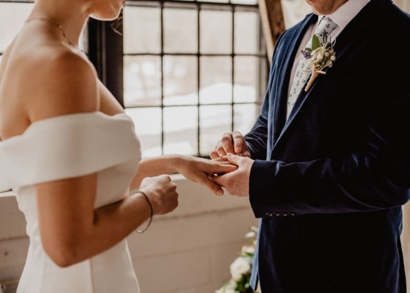 A bride and groom exchange rings during their wedding ceremony. A bride and groom exchange rings during their wedding ceremony.